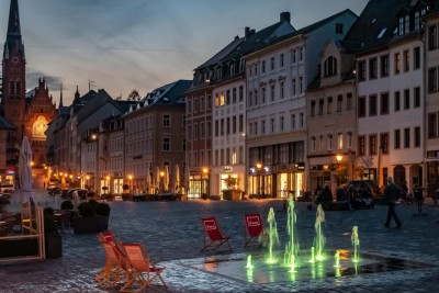 Der Altenburger Marktplatz, zu sehen sind außerdem das leuchtende "Wasserspiel", drum herum stehen Klappstühle
