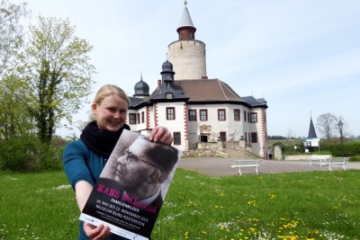 Franziska Huberty mit Ausstellungsplakat vor Burg Posterstein
