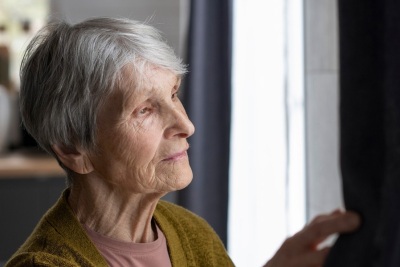 Seniorin schaut aus dem Fenster