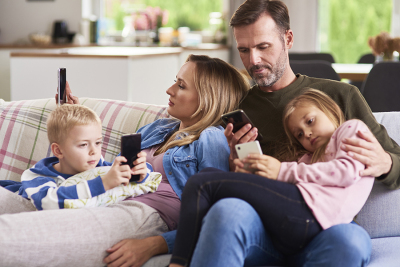 Eltern mit Kindern und Handys auf dem Sofa