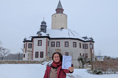 Museumsmitarbeiterin Marlene Hofmann mit dem neuen Winterferien-Rätsel vor Burg Posterstein