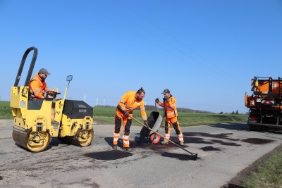 Mitarbeiter der Kreisstraßenmeisterei bessern Straßenschäden aus.