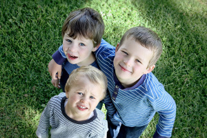 Drei Kinder auf Wiese die in Kamera schauen